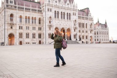 Macar parlamentosuna yakın bir kız. Turist - sırt çantalı bir kız Avrupa 'yı geziyor. Macaristan 'a seyahat, Avrupa turu.