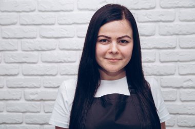 Beyaz tuğlalı arka planda esmer bir kız. Mesaj ve logo için yeri var.