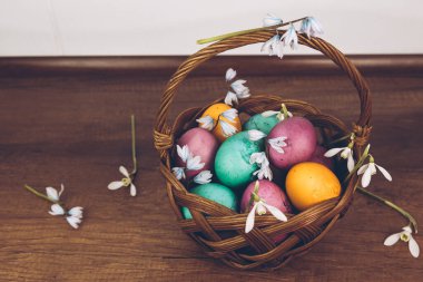 Paskalya geçmişi. Sepette paskalya yumurtası. Sarı, yeşil ve mor yumurtalarla süslü bir Paskalya sepeti ahşap bir masada duruyor..