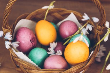 Paskalya geçmişi. Sepette paskalya yumurtası. Sarı, yeşil ve mor yumurtalarla süslü bir Paskalya sepeti ahşap bir masada duruyor..