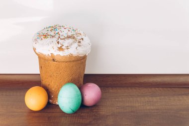 Paskalya yumurtası ve pasta. Tahta bir masada paskalya pastası ve farklı renklerde Paskalya yumurtaları - sarı yumurtalar, yeşil ve mor yumurtalar.