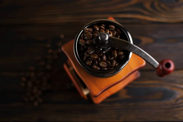 Coffee mill on a wooden table in a rustic style. Coffee beans in a manual coffee mill on a rustic table with a dark color.