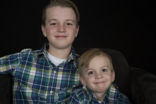 Два симпатичных брата портрет в одинаковых рубашках улыбаясь ок — стоковое фото