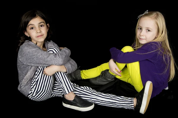 Two cute girls sitting casually looking at the camera — Stock Photo, Image