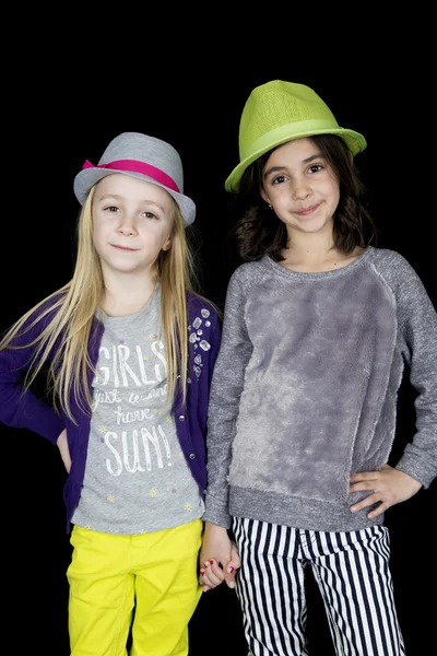 Two adorable girls holding hands wearing cute hats — Stock Photo, Image