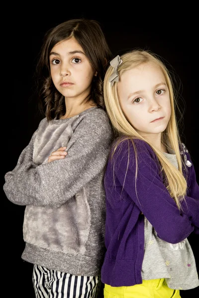 Dos chicas lindas de pie con los brazos cruzados sin sonreír — Foto de Stock
