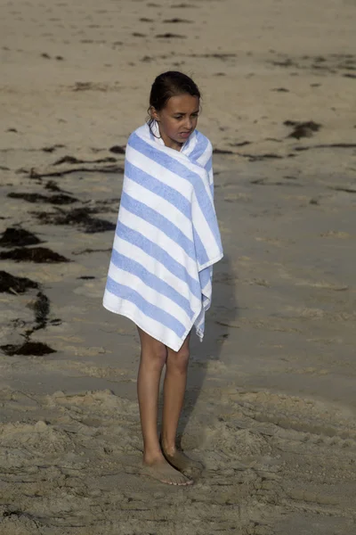 Tan Caucasian girl wrapped in a striped towel standing on the be — Stock Photo, Image
