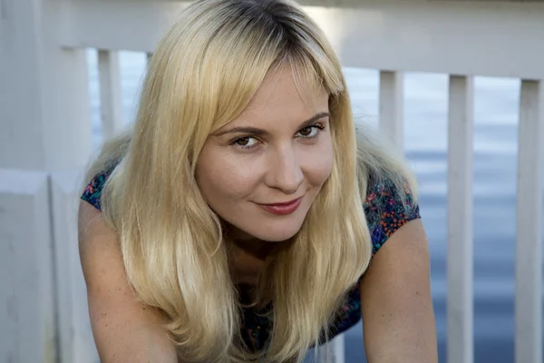 Blond female model at the lake lwaning forward looking at the ca — Stock Photo, Image