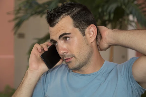 Dark haired male model in stressful cell phone conversation — Stock Photo, Image