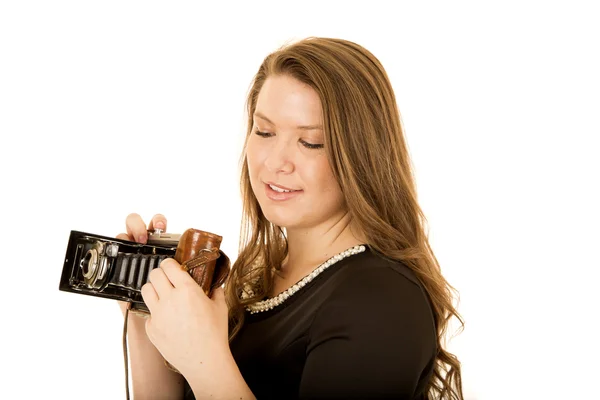 Jonge vrouw kijken neer op een antieke camera — Stockfoto