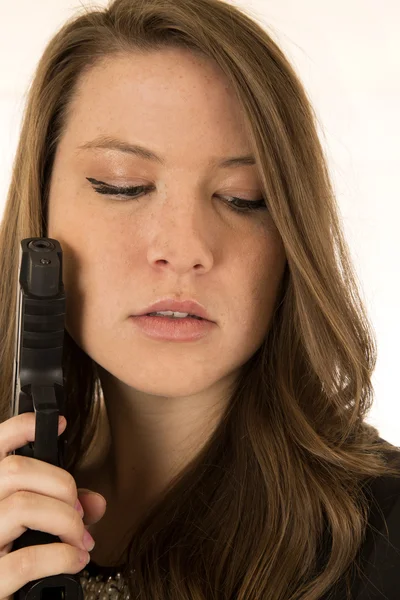 Brunette female holding a black pistol looking down — Stock Photo, Image