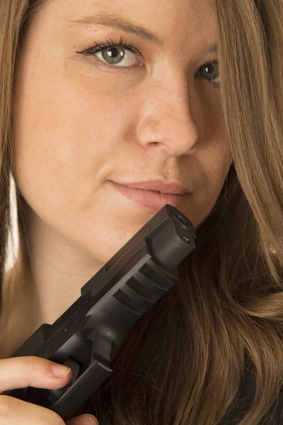 Protrait of a brunette woman peering over a black gun — Stock Photo, Image