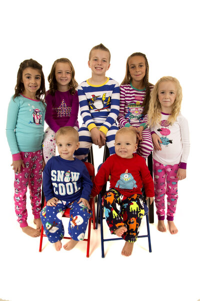 Seven beautiful young children wearing winter pajamas smiling