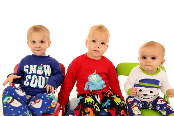 Tres chicos jóvenes lindos sentados usando pijamas de invierno —  Fotos de Stock