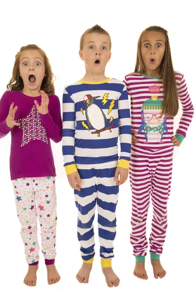 Tres niños vistiendo pijamas de invierno con un exp facial sobresaltado — Foto de Stock