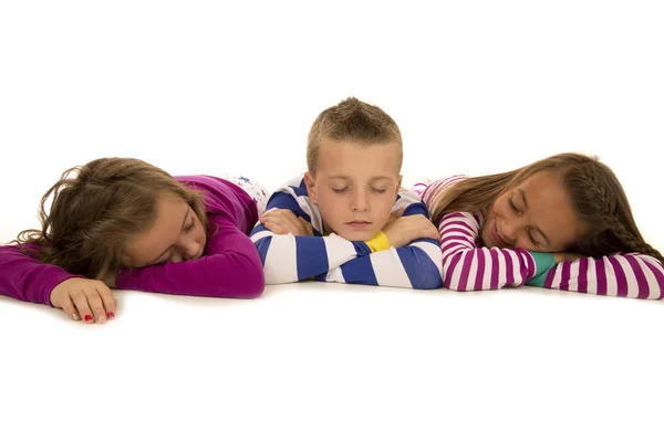 Tre bambini sdraiati in pigiama fingendo di dormire — Foto Stock