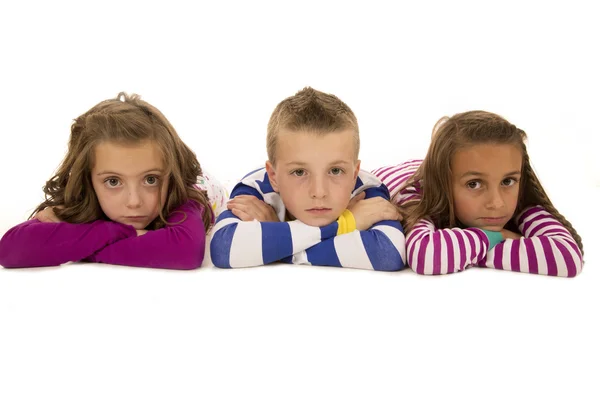 Crianças deitadas de pijama olhando para a câmera — Fotografia de Stock