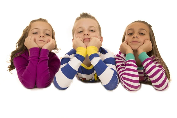 Hermosos niños pequeños con pijamas apoyados en los codos —  Fotos de Stock