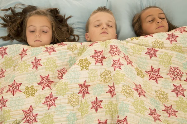 Garçon et deux filles endormis sous une couverture — Photo