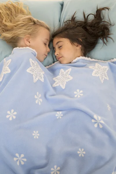 Two young girls in bed asleep under a snowflake blanket — Stock Photo, Image