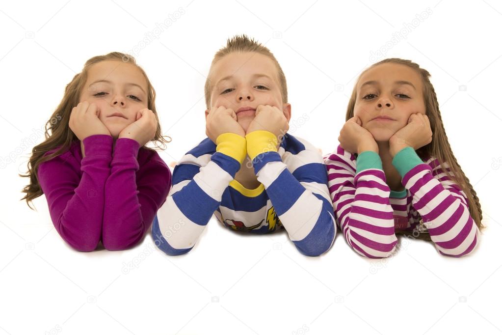 Beautiful young children wearing pajamas leaning on elbows