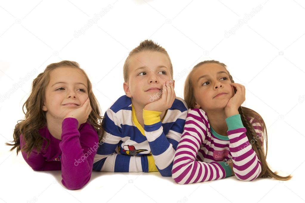 Three children wearing winter pajamas looking up smiling