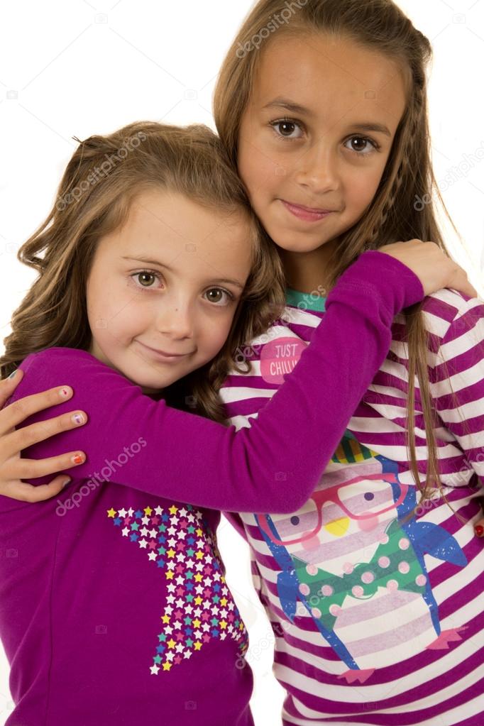 Two girl cousins wearing christmas pajamas hugging each other