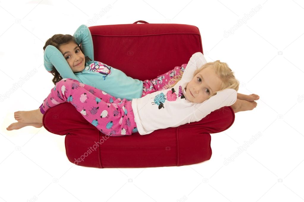 Two cute girls relaxing in a red chair
