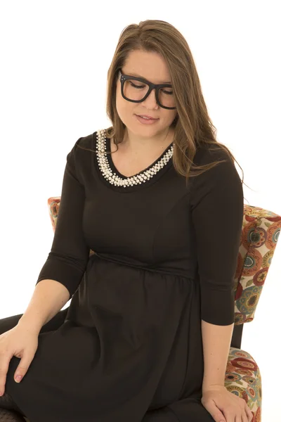 Model sitting wearing a dress and black glasses looking down — Stock Photo, Image