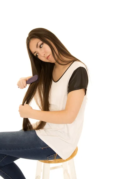 Asian American teen girl sitting and brushing her hair — Stock Photo, Image