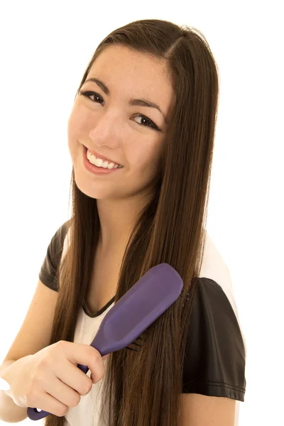 Красивая азиатская американская подросток расчесывает волосы улыбаясь — стоковое фото
