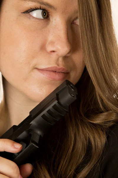 Morena modelo feminino olhando para os lados segurando uma pistola preta — Fotografia de Stock