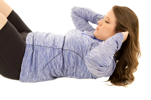 Female model doing sit ups wearing blue top with a white backgro — Stock Photo, Image