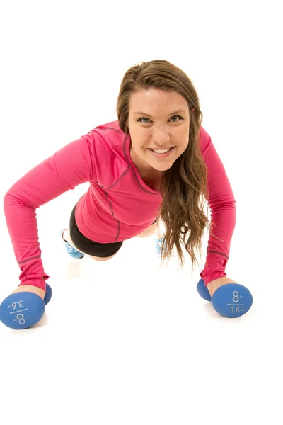 Woman doing pushups on barbells looking at camera smiling — Stock Photo, Image