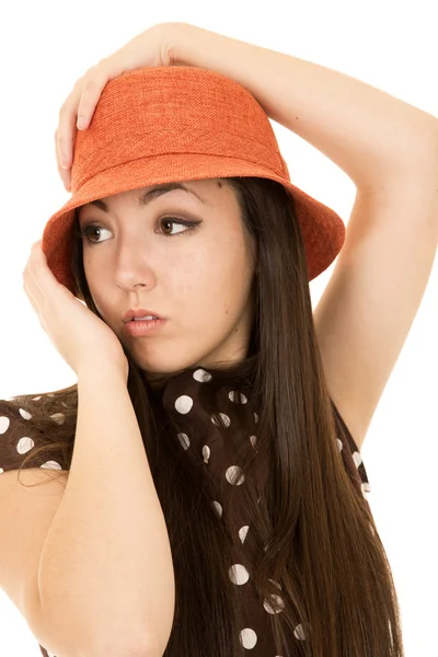 Modelo adolescente usando chapéu laranja olhando para a mão afastada em seu chapéu — Fotografia de Stock