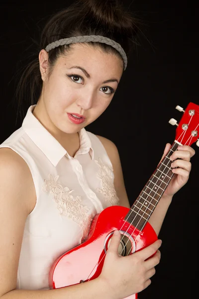 Portrait of a teen gilr playing a ukulele with no smile — Stock Photo, Image
