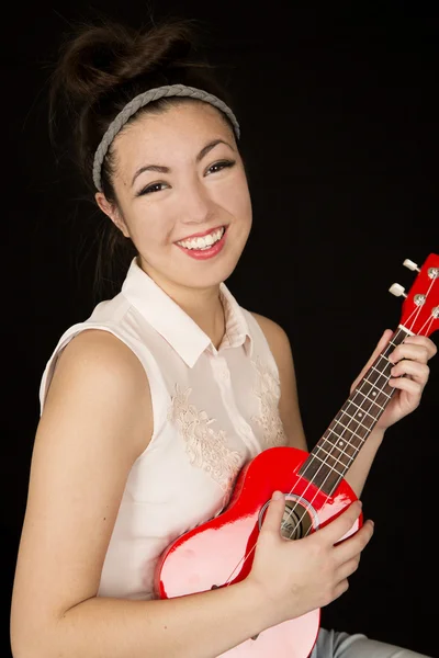 Attractive teen girl model playing a ukulele smiling — Stock Photo, Image