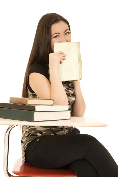 Mujer estudiante sentada en su escritorio ocultando su cara con libro sm —  Fotos de Stock