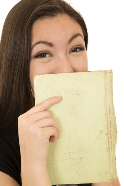 Jeune étudiante riant derrière un livre couvrant son visage — Photo
