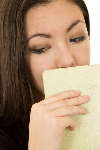 Junges Weibchen schaut nach unten und versteckt Mund mit Buch — Stockfoto