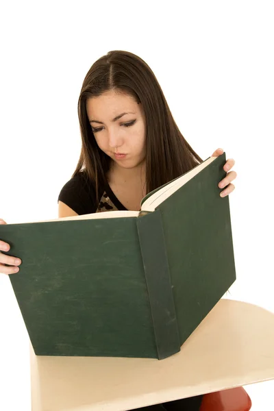Female student reading a large book with a confused expression — Stock Photo, Image