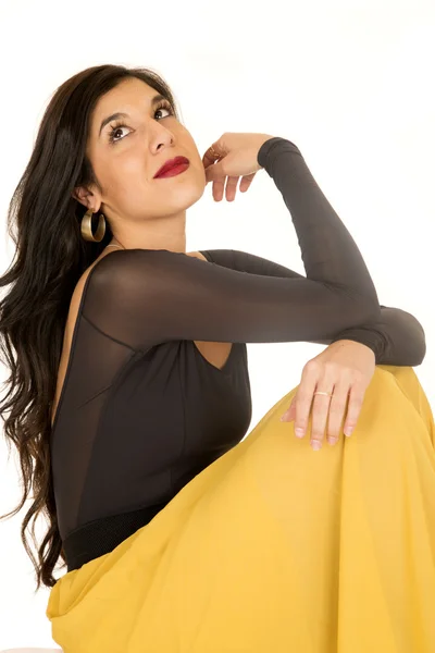 Beautiful brunette woman sitting wearing yellow skirt looking up — Stock Photo, Image