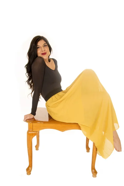 Female model wearing a black top and yelllow skirt sitting on co — Stock Photo, Image