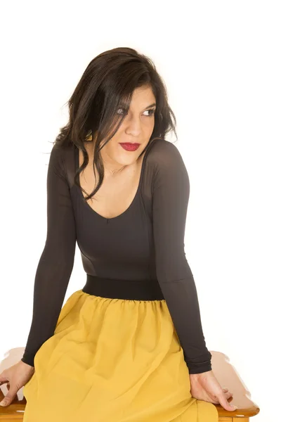 Female model sitting wearing black top and yellow skirt — Stock Photo, Image