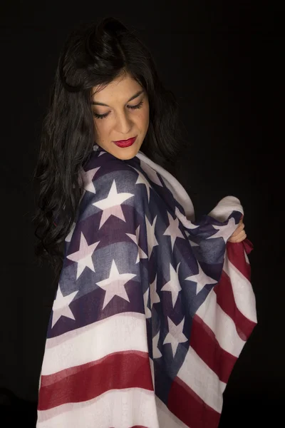Mulher bonita com bandeira americana drapeado no ombro olhando fazer — Fotografia de Stock