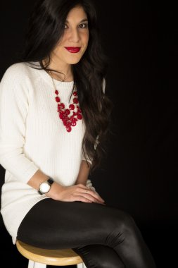 Bir tabure kırmızı kolye ve parlak kırmızı l üzerinde oturan güzel kadın