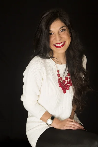 Pretty dark woman sitting smiling white sweater red necklace — Stock Photo, Image