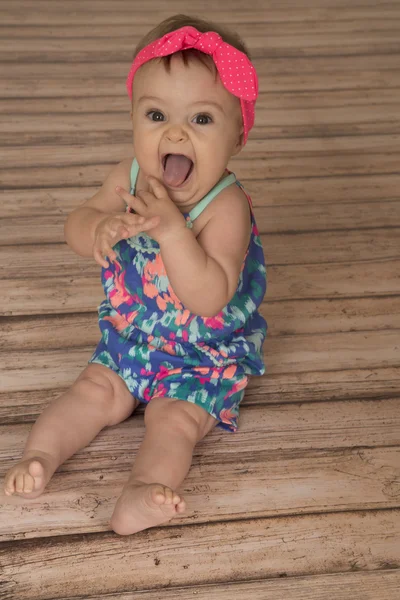 Excited baby girl hands up tongue out pink bow