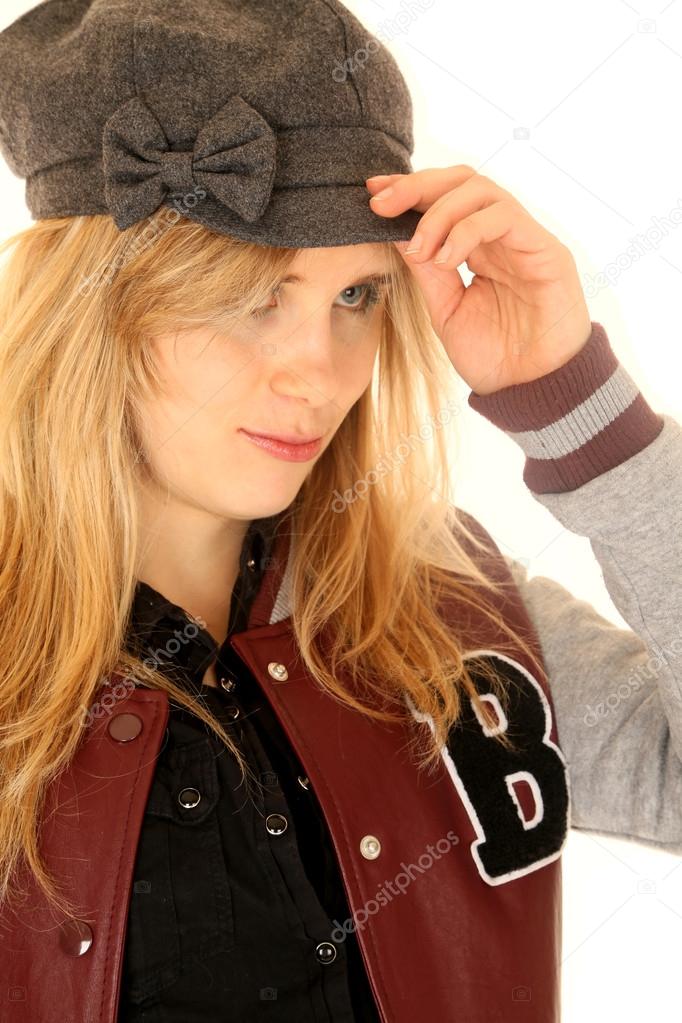 Girl wearing a letterman jacket while adjusting her hat Stock Photo by