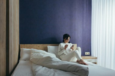 Saldırgan kadın dizüstü bilgisayarla kanepede yatıyor.